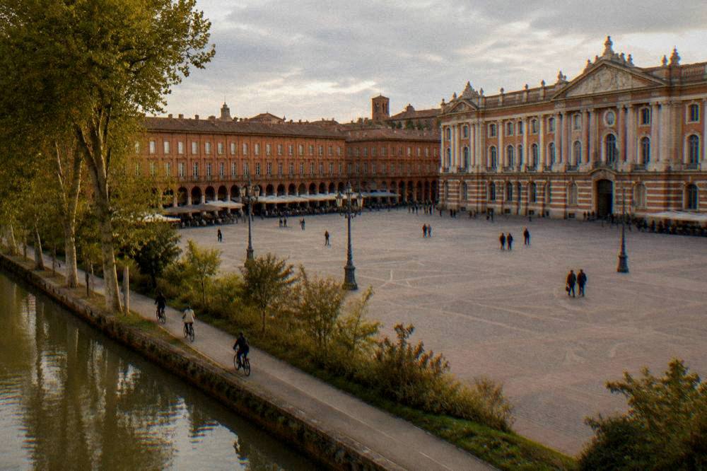 Cyclists riding along a tree-lined canal path on the edge of Toulouse