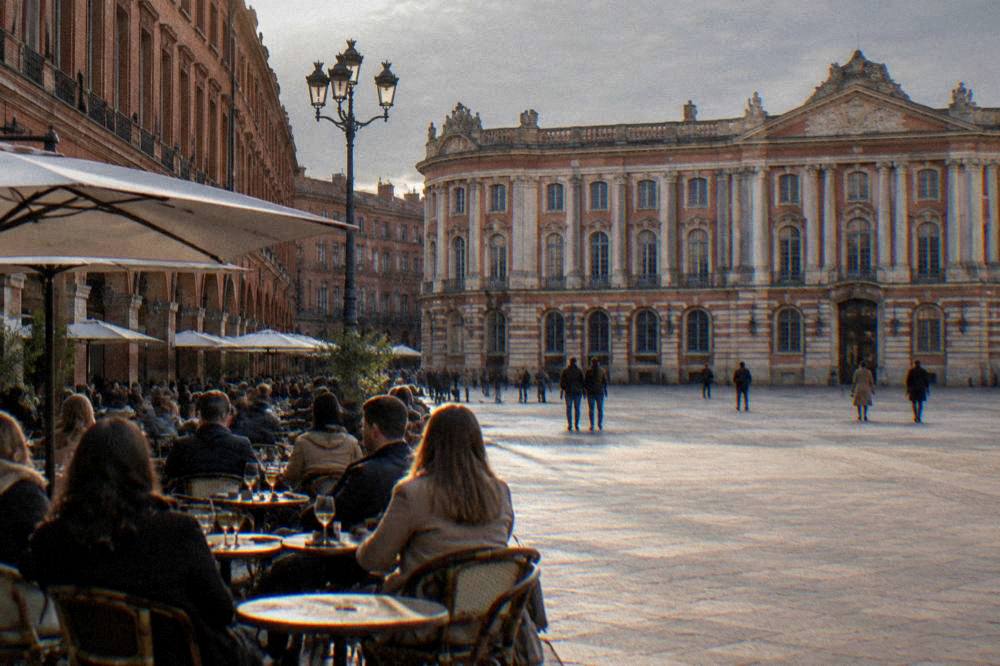 People eating at outdoor tables on a sunlit street in a French city center