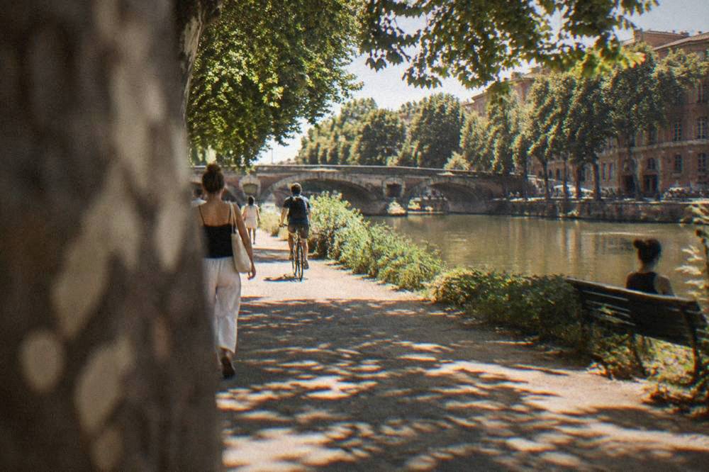 A shaded park path along a canal in Toulouse on a warm summer afternoon