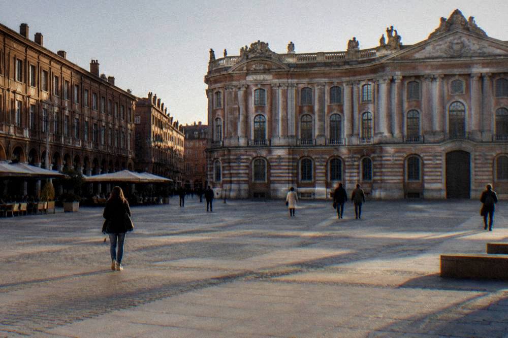 A historic building facade with arched windows near a grand city square in Toulouse