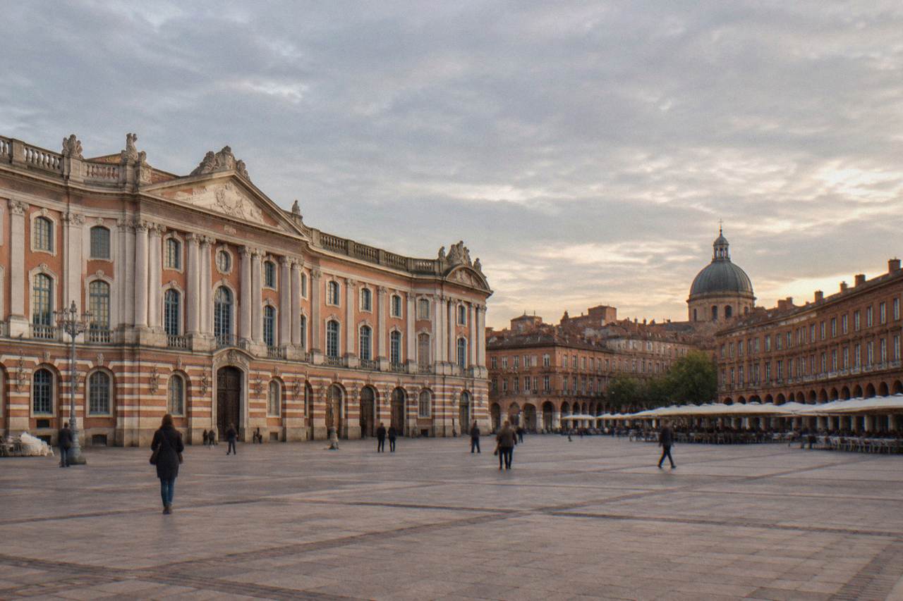 Toulouse rooftops with pink brick buildings and the dome of a church in the distance