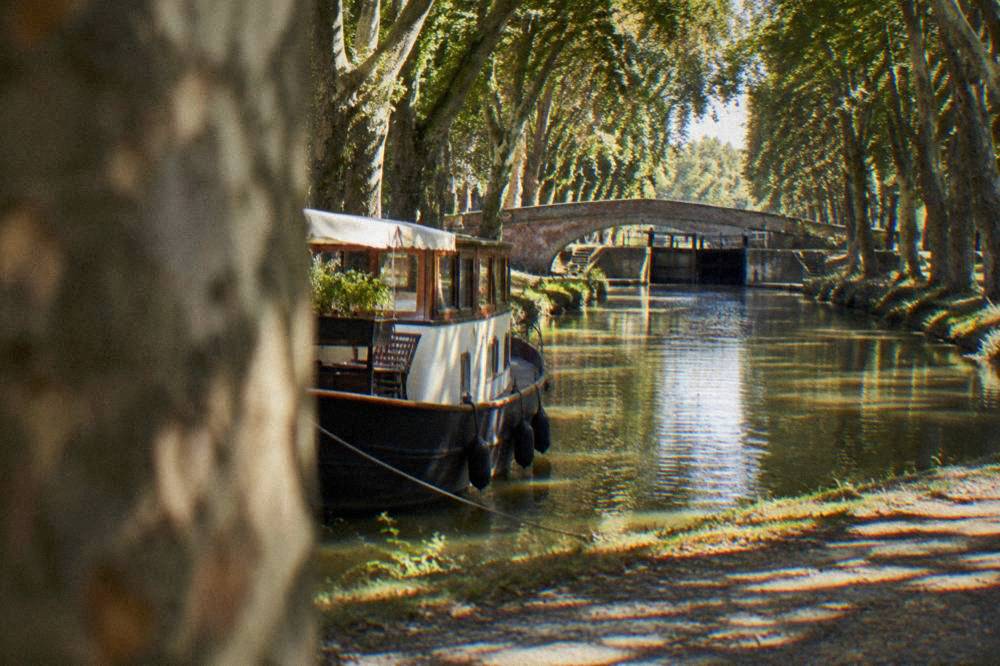A canal boat moored on the Canal du Midi under plane trees in Toulouse