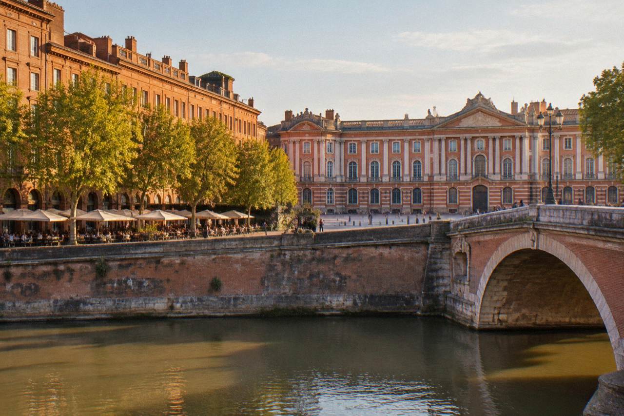 Pink brick buildings along a sunlit Toulouse street with the Capitole in the background