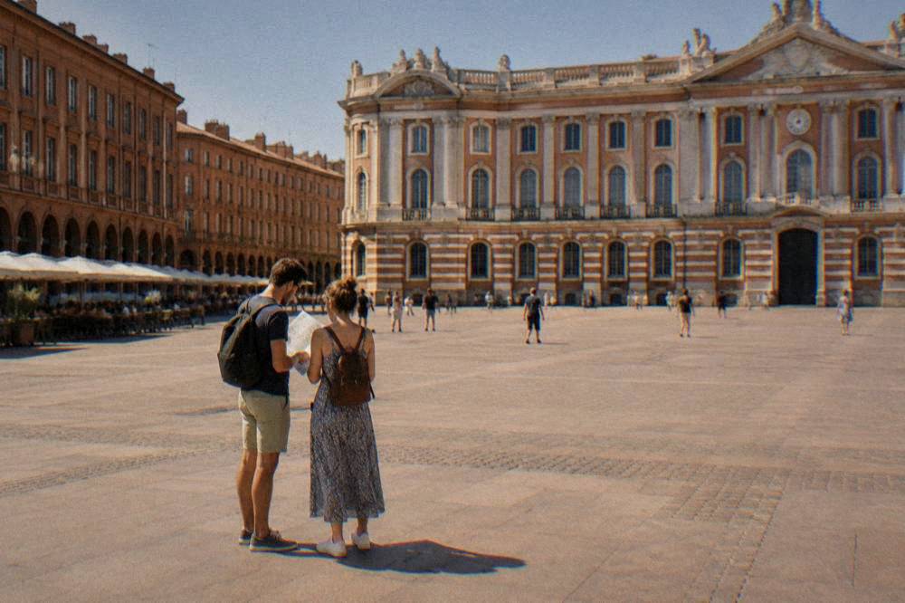 A couple reading a city map on a bench in a Toulouse square