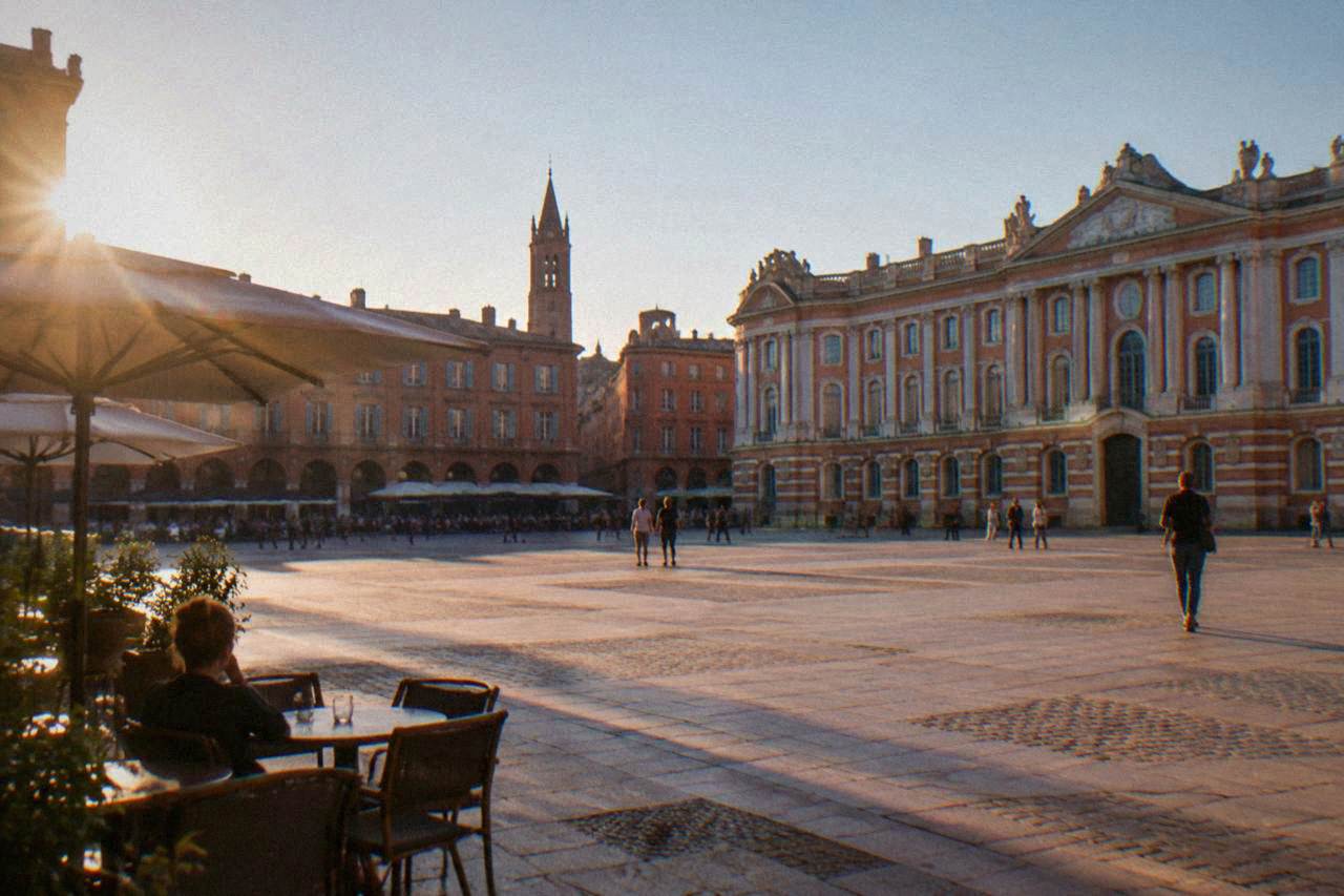 Pink brick buildings and a church tower in Toulouse under a clear sky