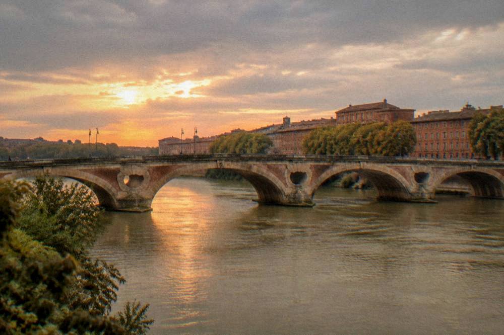 The Garonne river in Toulouse at sunset with the Pont Neuf and pink facades