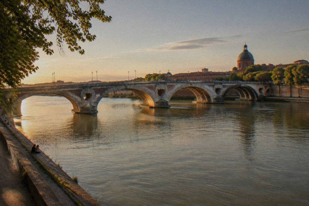 Wide view of the Garonne river in Toulouse with the Pont Neuf bridge at golden hour