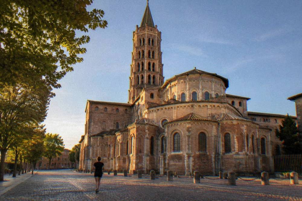 Basilica of Saint-Sernin in Toulouse seen from the square with its brick tower against a blue sky