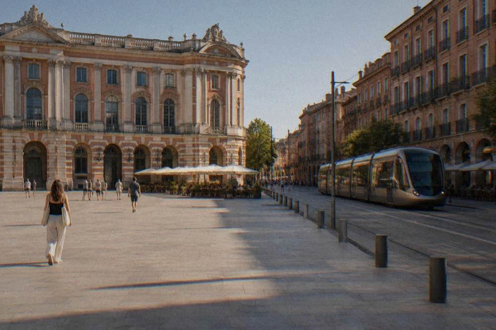 Modern tram on a Toulouse street lined with pink brick apartment buildings