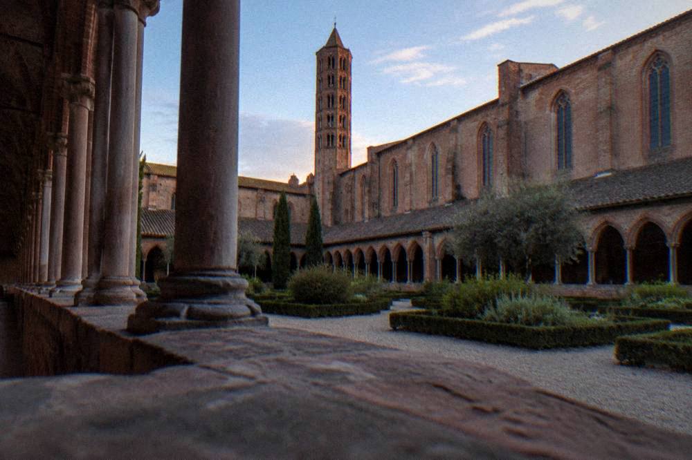 Cloister of the Couvent des Jacobins in Toulouse with brick arches and a garden
