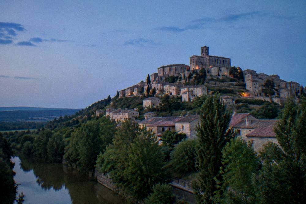 Hilltop village of Cordes-sur-Ciel seen from below with stone buildings rising above the trees