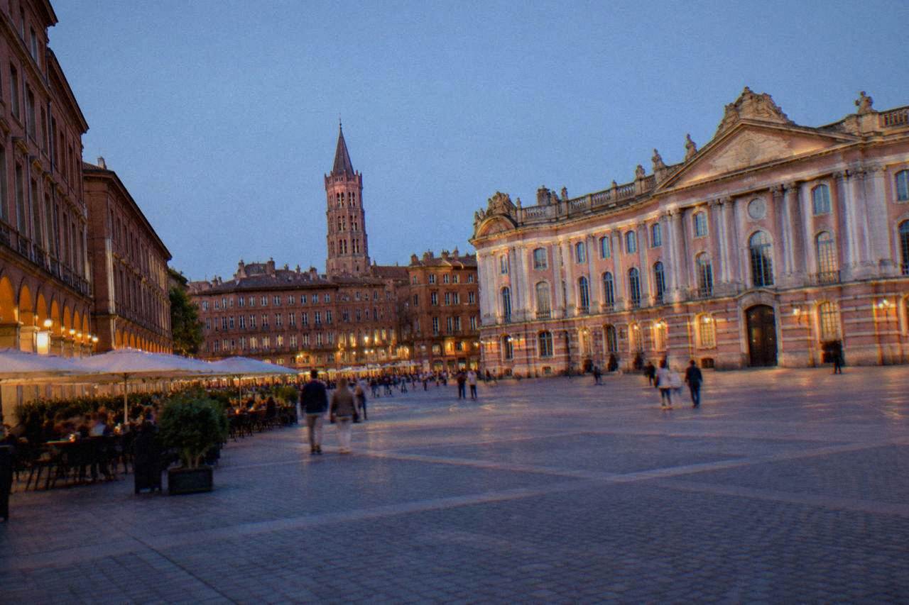 Pink brick buildings and a church tower in Toulouse under a clear sky
