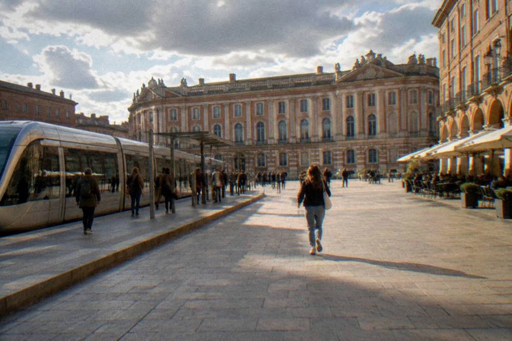 A modern tram and passengers at a station platform in a French city