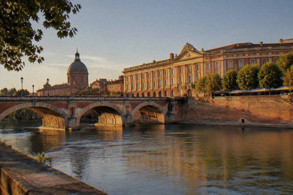 A rose-colored brick street in Toulouse with facades glowing in late afternoon sun