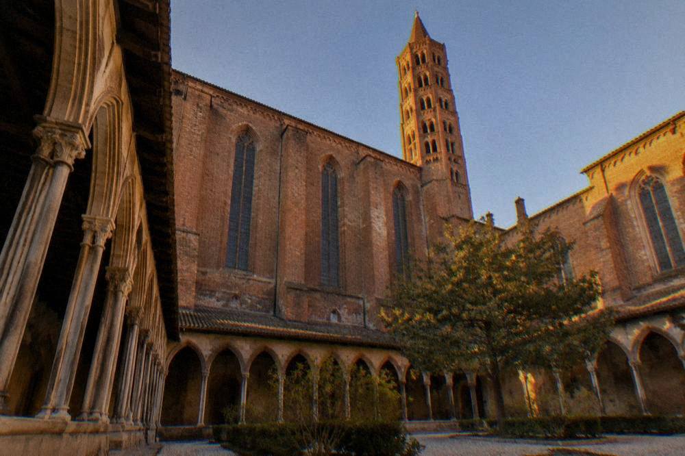 The cloister of the Couvent des Jacobins with tall stone arches and a courtyard