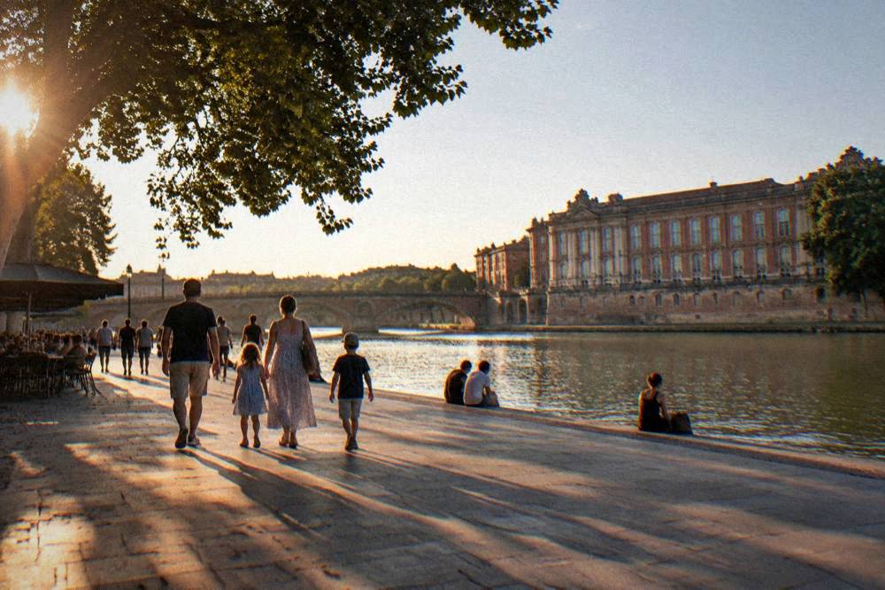 Families walking beside the Garonne river in Toulouse on a sunny afternoon