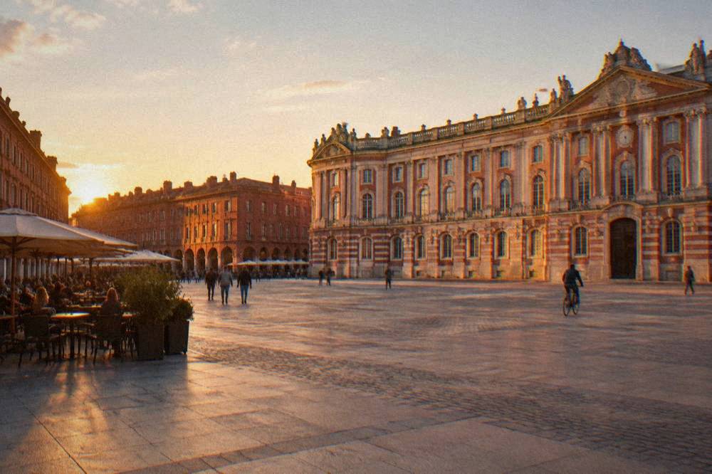 Sunset light turning Toulouse brickwork deep red-orange beside the Garonne