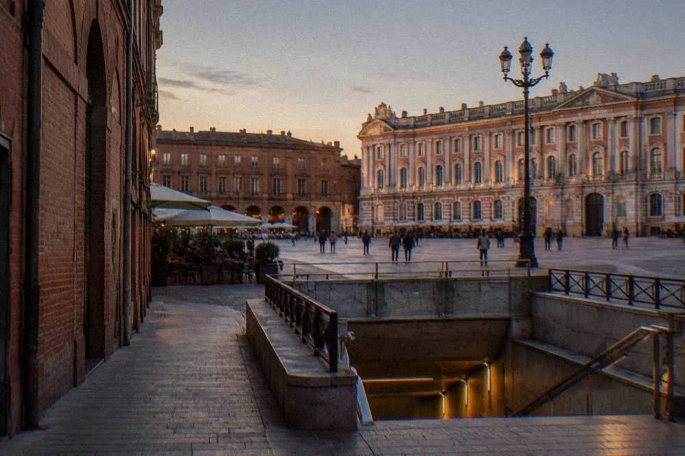 Pink brick alley in Toulouse with a metro entrance in the foreground