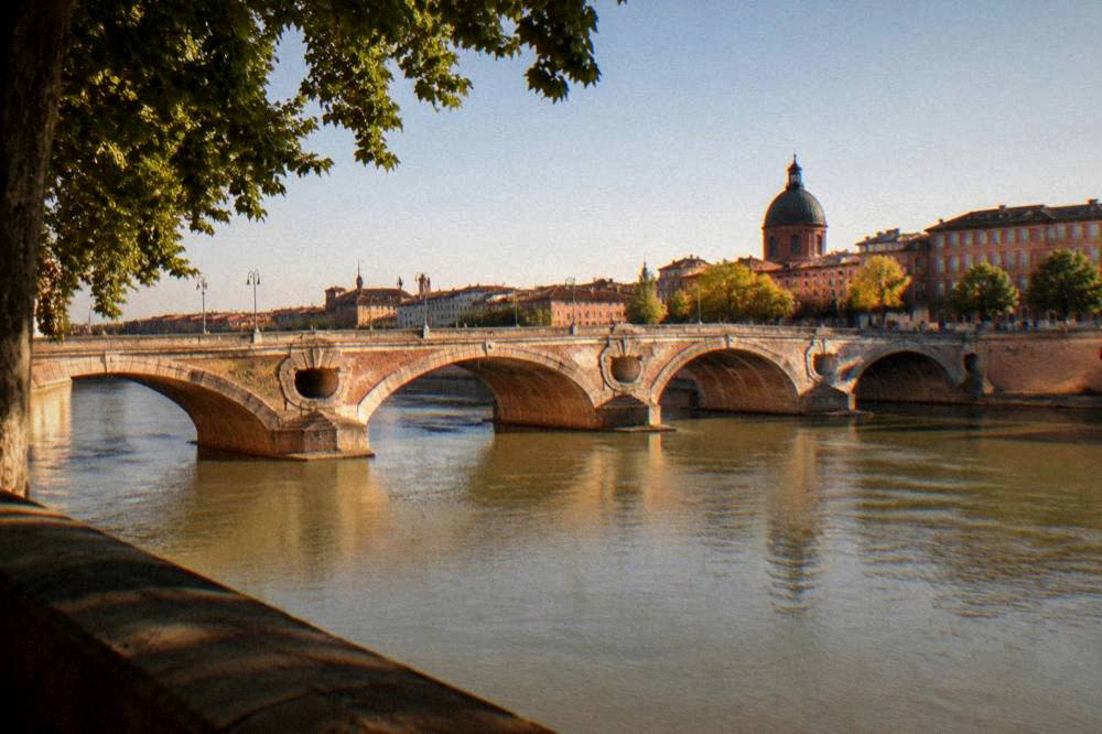 Evening view of the Pont Neuf and pink riverfront buildings in Toulouse