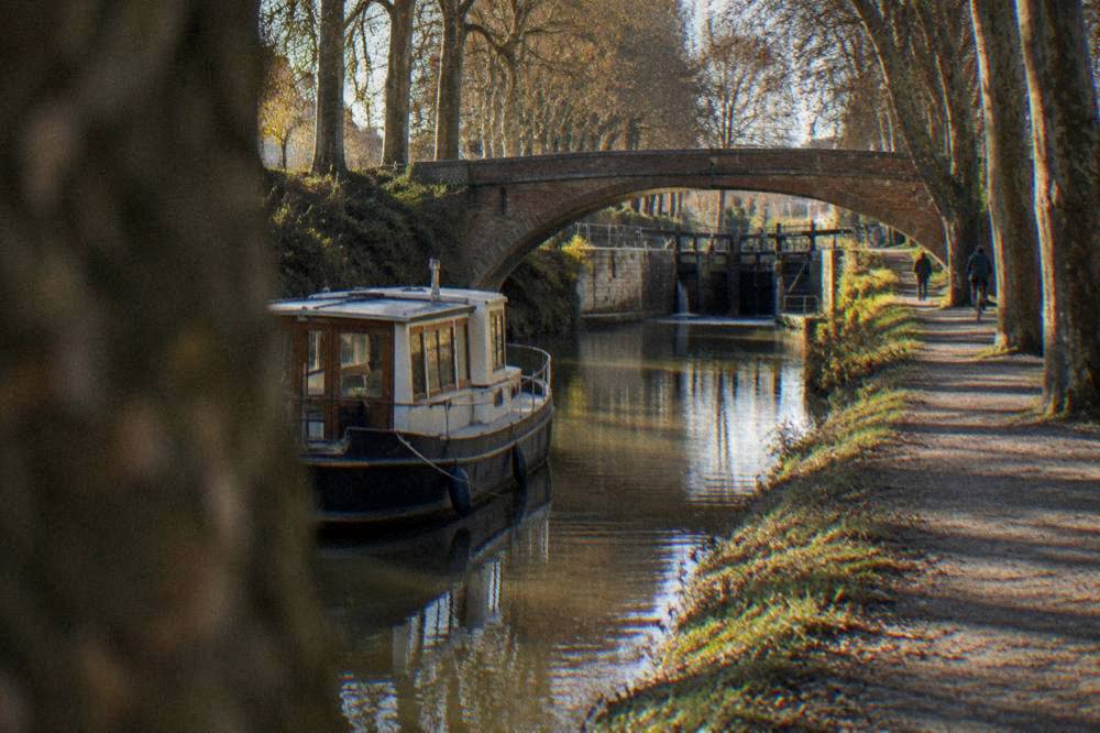 A canal boat moored beside a stone bridge on the Canal du Midi