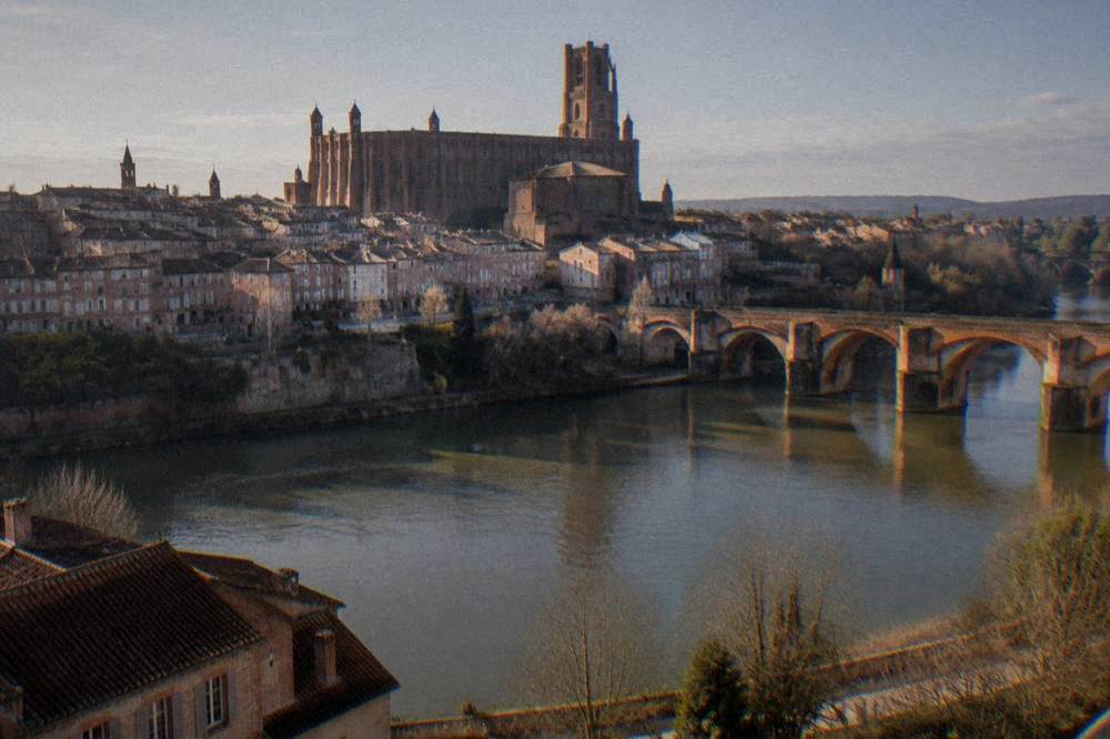 A red brick cathedral towering over the town of Albi seen from across a river