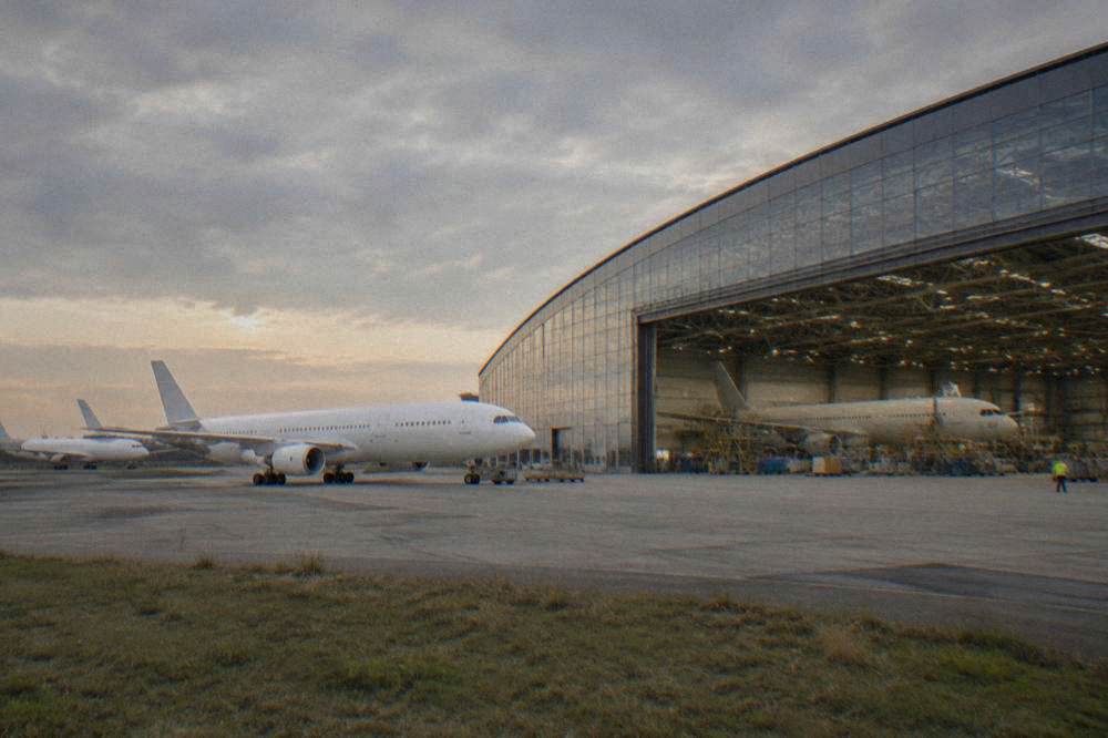 A wide-body airliner in final assembly inside a large factory hall