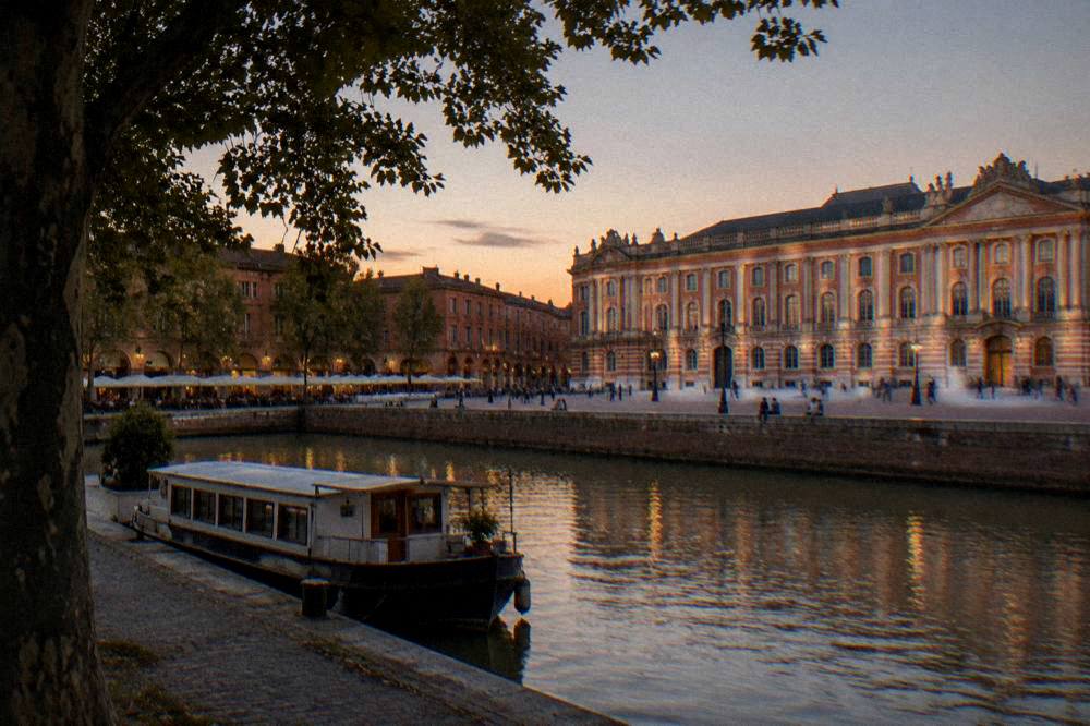 A tree-lined canal with a boat moored at the bank in a French city