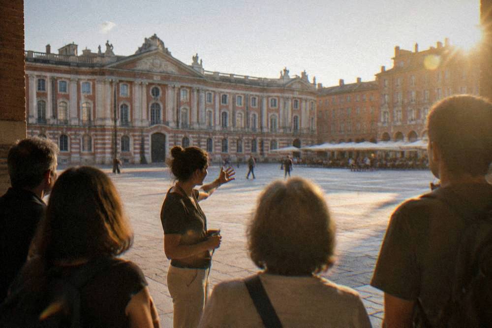 A guide addressing a small group of visitors in a Toulouse square