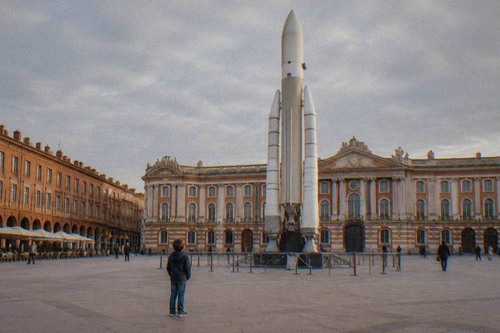 A child looking up at a full-scale rocket standing outside a space museum