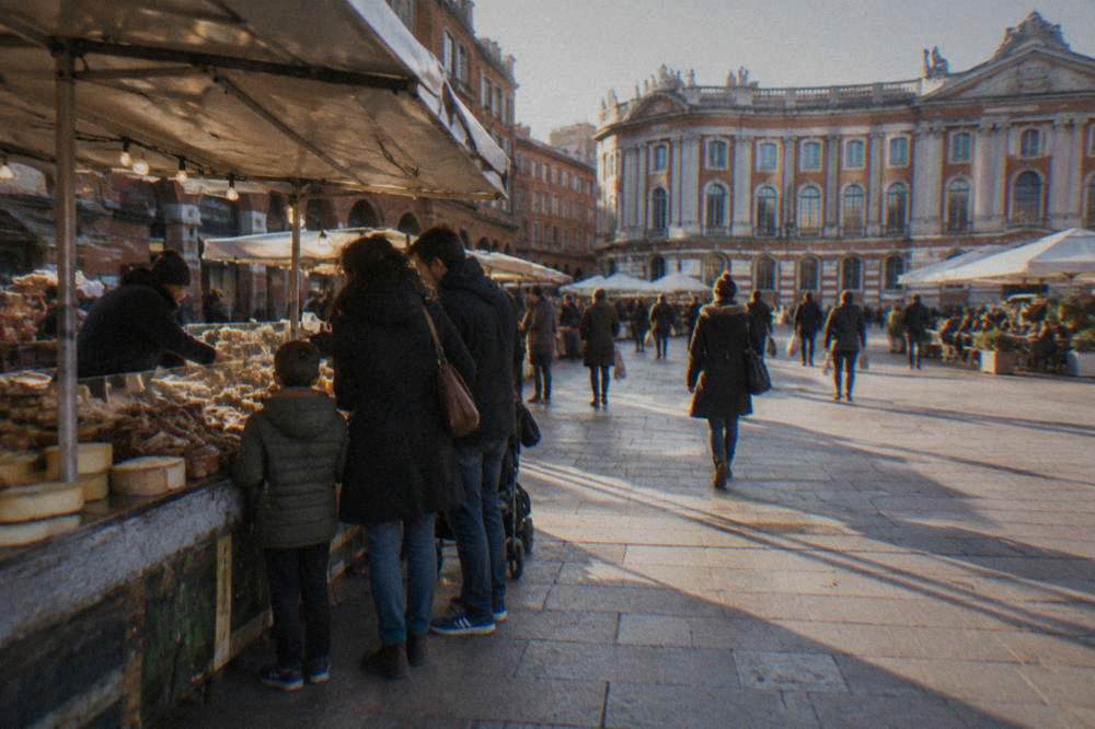 A family sharing food at a busy covered market stall in Toulouse